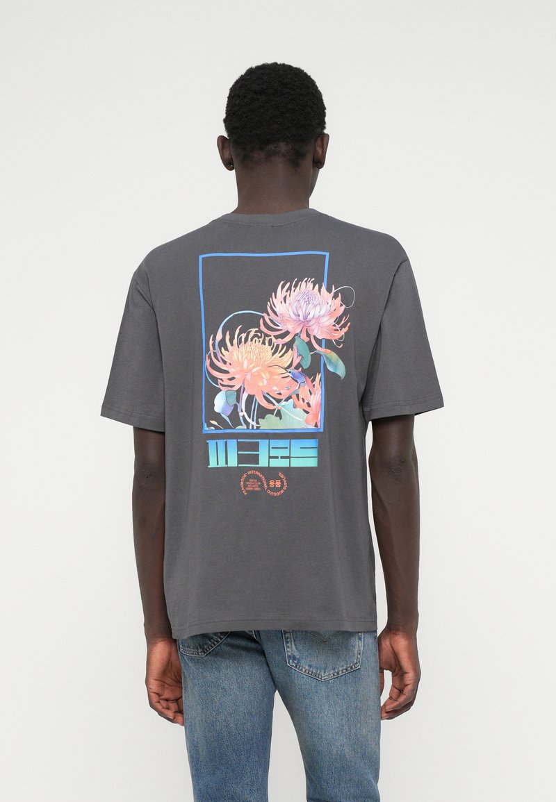 Graues Baumwoll-T-Shirt mit einer bunten Grafik von Blumen und geometrischen Formen auf der Rückseite. Rundhalsausschnitt und kurze Ärmel.