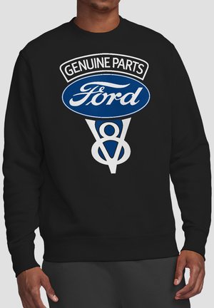 Black sweatshirt with white and blue "Genuine Parts Ford V8" logo worn by person with dark skin and dark pants.
