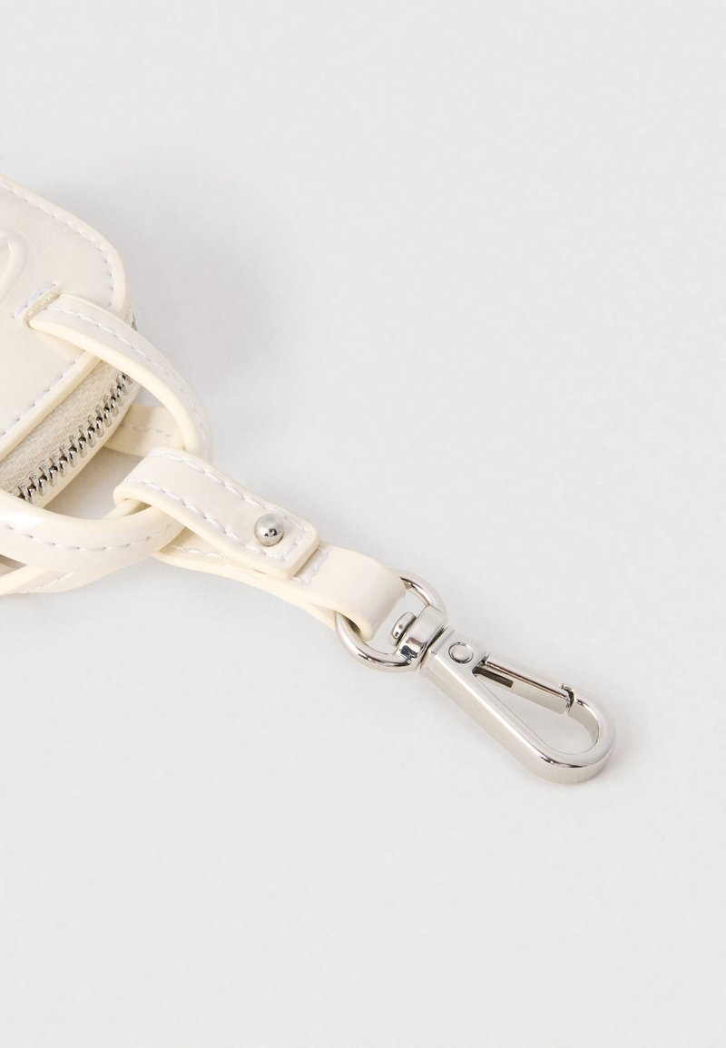 Weißer Lederriemen mit silbernem Karabinerverschluss aus Metall auf hellem grauem Hintergrund.