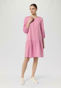 Rosa Kleid mit rundem Halsausschnitt, Dreiviertelärmeln und einem gerafften Rock. Hergestellt aus glattem Material, verfügt es über ein dezentes Falten-Detail.