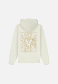 Cremfarbener Hoodie mit einem großen, filigranen goldenen Grafikdesign auf der Rückseite, das wirbelnde Muster und ein zentrales Emblem zeigt.