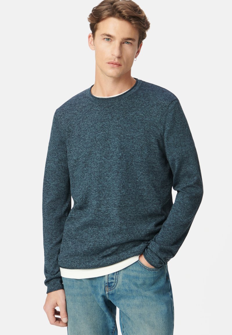 Donkerblauwe crewneck sweatshirt met lange mouwen, gestructureerde stof en contrasterende witte binnenkraag, gecombineerd met lichtblauwe jeans.