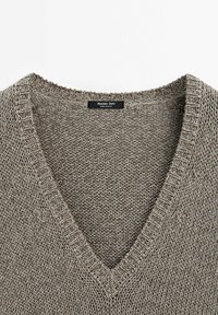 Pull en tricot à col en V de couleur marron clair, présentant une texture à tissage lâche et une étiquette indiquant "Massimo Dutti, Fabriqué en Espagne".