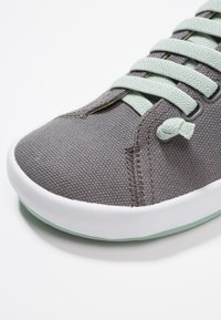 Baskets en toile grises avec des lacets vert clair, une semelle en caoutchouc blanc et une surface texturée. Comprend une pointe arrondie et des accents cousus.