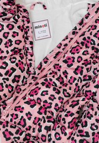 Chaqueta acolchada rosa con estampado de leopardo negro y fucsia, con bordes con volantes, cremallera frontal y un suave forro interior blanco.