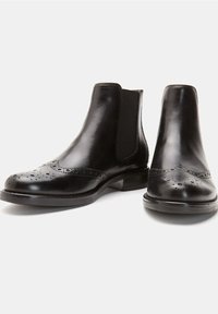 Czarne skórzane buty Chelsea z detalami brogue, elastycznymi panelami po bokach i niskim obcasem. Gładka faktura; zaokrąglony nosek z perforacjami.