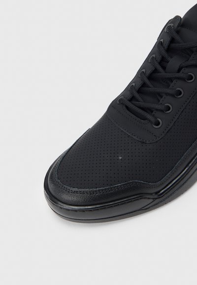 Μαύρο αθλητικό παπούτσι με διάτρητο συνθετικό επάνω μέρος, επίπεδα μαύρα κορδόνια, επένδυση στον αστράγαλο και λαστιχένια σόλα. Κομψός σχεδιασμός με στρογγυλεμένη μύτη.