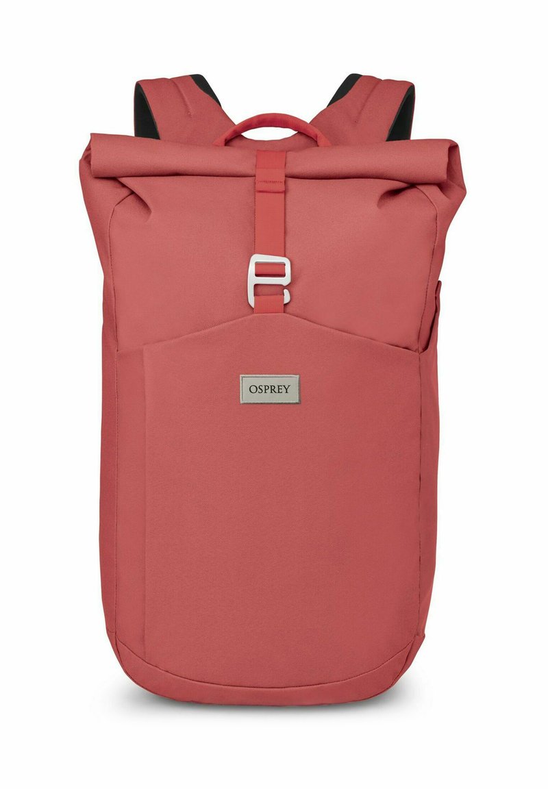 Mochila de color rosa con diseño de parte superior enrollable, correas ajustables y un bolsillo frontal. Presenta una etiqueta de marca plateada y está fabricada con un tejido duradero.