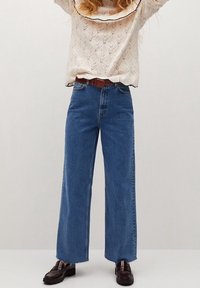 Jasnoniebieskie szerokie jeansy z wysokim stanem i postrzępionym dołem, zestawione z kremowym swetrem z dzianiny z ozdobnym dekoltem w kształcie fali.