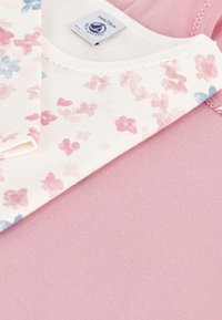 Blomstermønstret bomullstopp i myk rosa og kremfarge med små blå og rosa blomster; glatt tekstur, blondedetaljer i halsen.