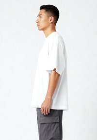 Valge puuvillane T-särk lühikeste varrukatega ja mugava lõikega, kombineeritud hallide cargo-pükstega, millel on küljetaskud ja tekstuuriga kangas.