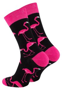 Black socks with a pattern of pink flamingos, featuring a pink ribbed cuff and toe accents. Made from soft, stretchy fabric.