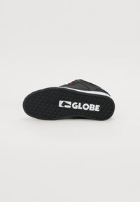 Musta skeittikenkä, jossa on teksturoitu kumipohja ja näkyvä valkoinen "GLOBE"-logo. Ylärangassa punaisia yksityiskohtia.