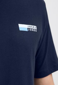 T-shirt blu navy in morbido cotone con maniche corte, dotata di un design grafico del logo in bianco e azzurro sul petto.