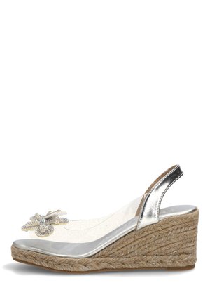 Sandalia de cuña plateada con plataforma de yute tejido, tira transparente y mariposa decorativa de pedrería en el empeine.