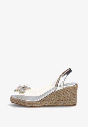Sandalia de cuña plateada con plataforma de yute tejido, tira transparente y mariposa decorativa de pedrería en el empeine.