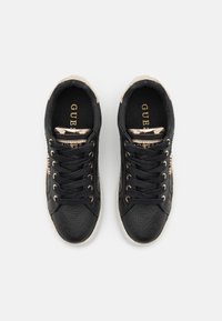Sneakers neri con un motivo testurizzato, dettagli in tono oro, punta rotonda e lacci neri. L'interno presenta una soletta nera con logo.
