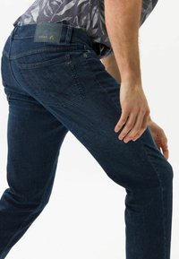 Mörkblå denimjeans med en åtsittande passform, med en klassisk femfickdesign och en märkesläderlapp på midjebandet.