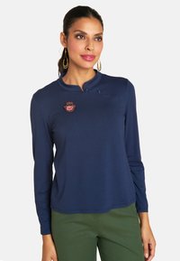 Langarmshirt in Marineblau mit runder Kragenform, ausgestattet mit dekorativen Knöpfen und einem bunten gestickten Design auf der linken Seite.