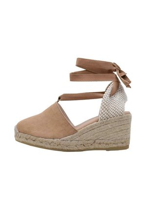 Espadrille à talon en toile marron avec des lanières entrecroisées, détail tissé à l'arrière et base enroulée de jute. Les accents comprennent un nœud à la cheville.