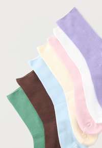 Gerippte Baumwollsocken in sieben Farben: lila, rosa, weiß, gelb, hellblau, braun und grün, in einem Farbverlauf angeordnet.