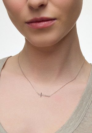 Srebrny wisiorek w kształcie krzyża na cienkim łańcuszku, charakteryzujący się minimalistycznym designem z przecięciem poziomego i pionowego pręta.