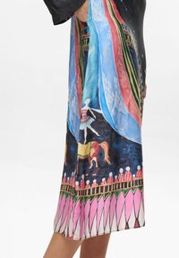 Vestido de seda con un estampado colorido que presenta bailarines, caballos y patrones geométricos. Base negra, diseño fluido, dobladillo a la altura de la rodilla.