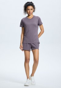 Vaalean violetti urheiluva outfit, joka koostuu lyhythiisistä paidasta ja shortseista. Valmistettu kosteutta siirtävästä materiaalista, jossa on sileä pinta.