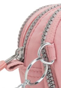 Różowa nylonowa saszetka z podwójnymi szarymi suwakami, srebrnym wykończeniem i mocowaniem na breloczek. Teksturowany materiał z gładkimi akcentami wzdłuż krawędzi.