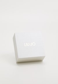 Scatola regalo argento con una finitura testurizzata, caratterizzata dal nome del brand "LIU·JO" in lettere dorate sulla parte superiore. Design quadrato e compatto.