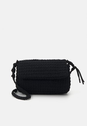 Sac à main tissé noir de forme rectangulaire, en tissu texturé, avec une anse tressée et un rabat fermé par des nouures sur les côtés.