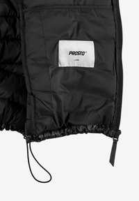 Wnętrze czarnej pikowanej kurtki z białą metką z napisem "PROSTO" i "LARGE", wyposażone w elastyczny dół oraz szczegóły ze sznurkiem do ściągania. Gładka faktura.