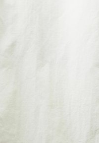 Tissu blanc texturé avec de légères plis et ombres, révélant un motif de tissage en lin naturel.