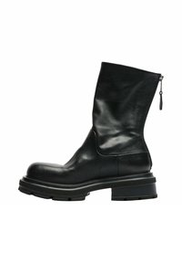 Bottino in pelle nera alla caviglia con punta arrotondata, design elegante e zip sul lato. Presenta una suola nera spessa e testurizzata.