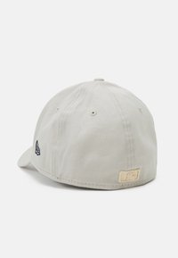 Svetlo siva bejzbol kapa s zakrivljenim vizirjem, tekstura tkanine in vezenim logotipom na strani. Vsebuje tudi malo oznako na hrbtni strani.