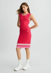 Rotes, geripptes Kleid mit ärmellosem Design, weißen Streifenakzenten am Kragen und Saum, ausgestattet mit zwei Vorder pockets mit Knopfdetails.