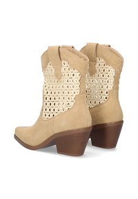 Botas de tobillo beige de ante con lados de tejido entrelazado, con un tacón ahusado y punta redonda. Destacan por su patrón similar a un encaje.