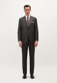 Traje gris a rayas con solapas muesca, dos botones, camisa de vestir blanca y corbata roja con patrón, combinado con zapatos de cuero negros.
