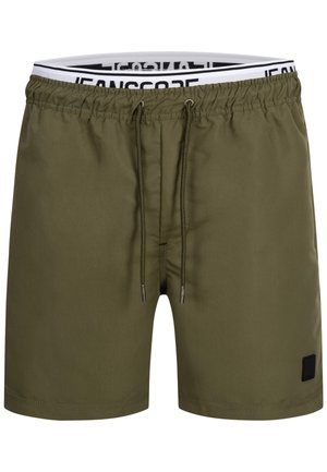 Shorts de bain vert olive avec taille élastique, cordon de serrage ajustable et petite étiquette logo noire sur le devant à gauche. Texture de tissu lisse.