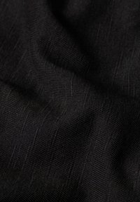 Tejido negro con una textura suave que presenta líneas sutiles y un ligero brillo, creando una apariencia clásica y elegante.