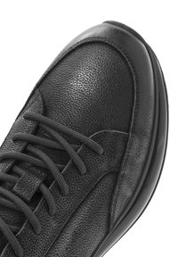 Zapatilla negra de cuero con acabado texturizado, con cordones redondos, cuello acolchado y suela negra brillante. Diseño clásico para uso casual.