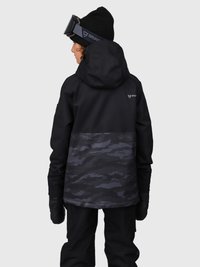 Persona que lleva chaqueta de esquí en camuflaje negro y gris, guantes negros, gorro y gafas de esquí, de espaldas, sobre un fondo gris.