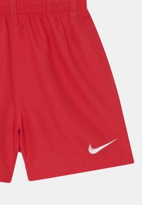 Shorts rouges avec une taille élastique, fabriqués en matériau léger. Présentent un logo Nike en argent sur le bas à gauche.