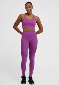 Paarse sportieve crop top en leggings gemaakt van rekbaar materiaal, met gestructureerde accenten en een aansluitend ontwerp.