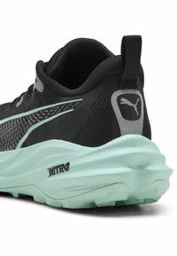 Baskets noires avec une tige en mesh texturé, semelle vert menthe et accents noirs. Comprend un onglet au talon et le logo Puma sur le côté.