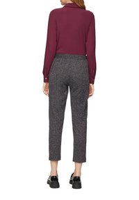 Chemise longue marron avec col, associée à un pantalon gris texturé à taille haute. Des chaussures noires épaisses complètent la tenue.