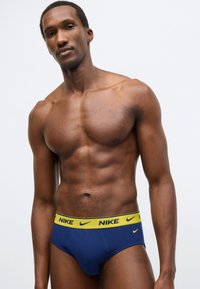 Ανδρικά εσώρουχα σε ναυτικό μπλε με κίτρινη ζώνη μέσης με λογότυπο Nike, διαθέτουν εφαρμοστή σχεδίαση και ομα�λή υφασμάτινη επιφάνεια.
