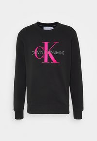 Sweatshirt noir en mélange de coton avec col rond. Présente un grand logo "CK" rose et gris ainsi que le texte "CALVIN KLEIN JEANS". Poignets côtelés.