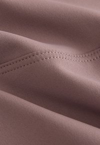 Pehme, tekstuuriga kangas tuhmi lavendlipruuni tooniga, millel on peened õmblused ja sile, kergelt elastne pind.