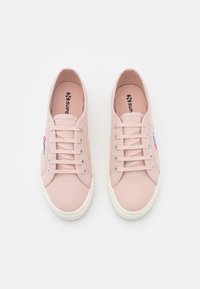 Sneaker in tela rosa chiaro con finitura texture, suole in gomma bianca e design con sei occhielli per i lacci. Logo "Superga" sul lato.
